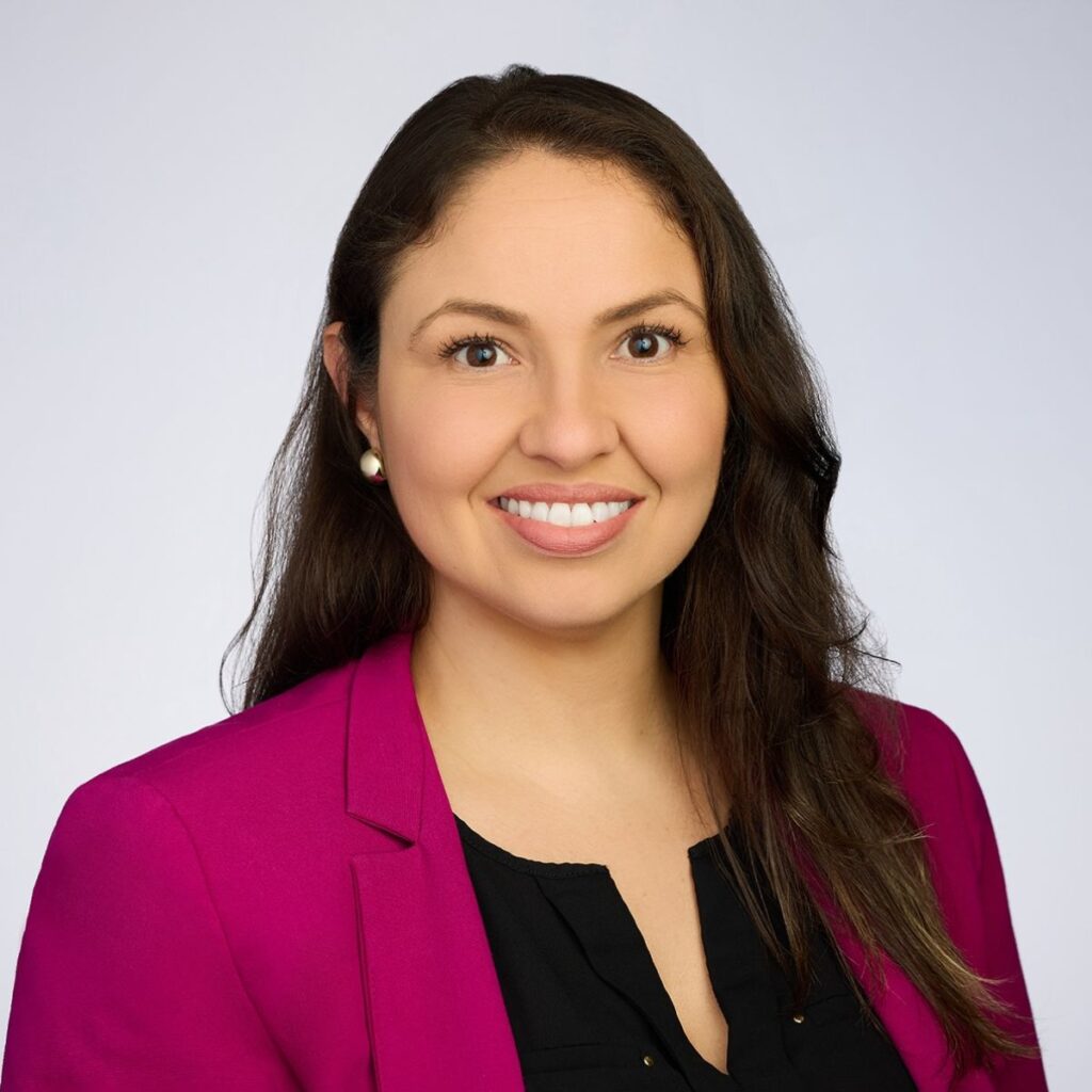 photo of a woman with long dark hair wearing a black top and magenta jacket